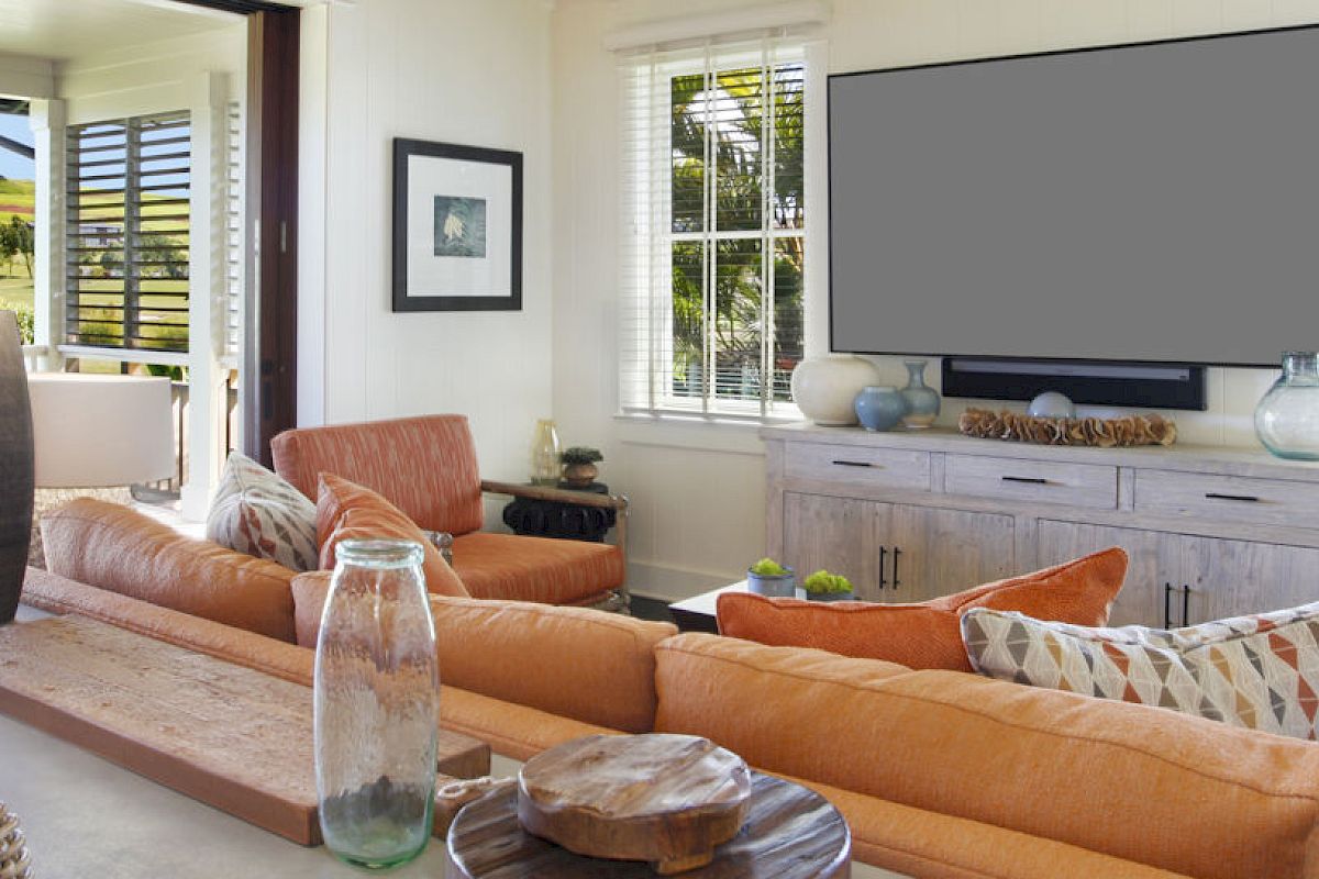 A modern living room with a golf course view, featuring leather sofas, a large TV, and sliding doors opening to an outdoor seating area ends the sentence.