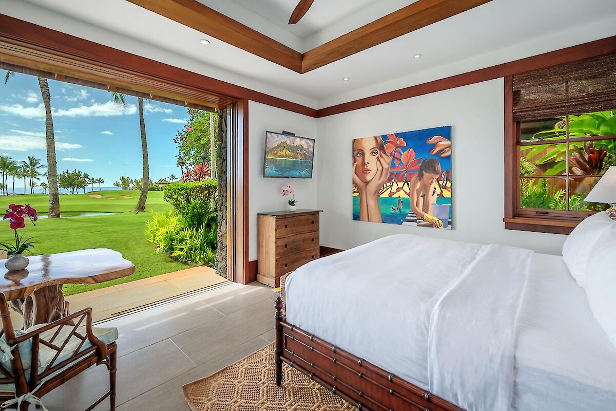 A bright tropical bedroom with a sliding door to a sunny lawn and palm trees, white beds, wooden accents, and coastal decor. End with period.