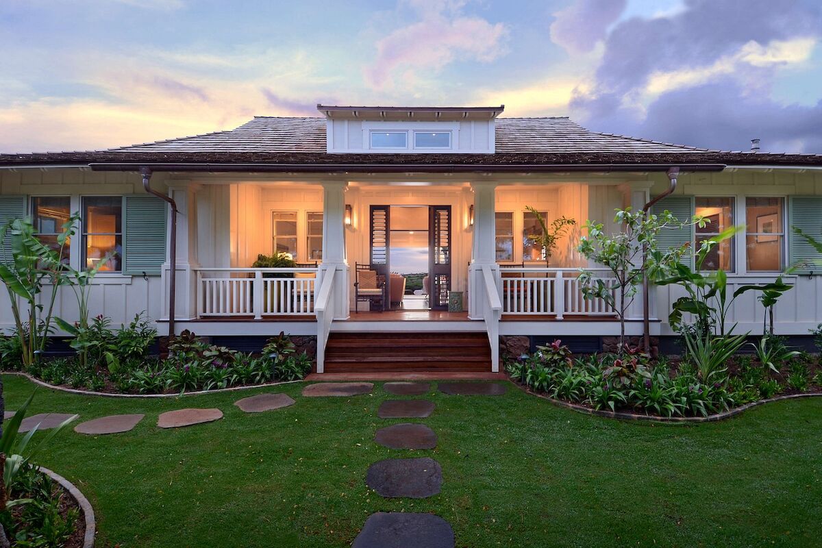 A charming house with a porch, surrounded by a lush garden and stepping stones leading to the entrance, under a colorful sky.